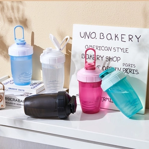 Five colorful plastic protein shaker bottles with mixing balls on a white desk