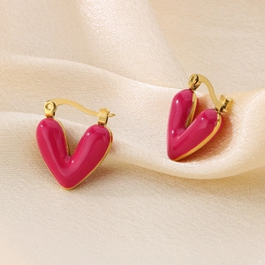 Detailed shot of pink enamel heart earrings on a cream silk background with gold plating