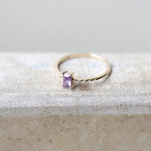 Macro shot of rectangular purple amethyst on textured gold band with fine bead detailing