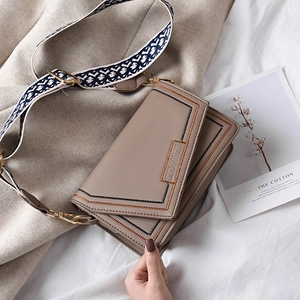 Sac à bandoulière kaki avec broderie ondulée et sangle géométrique sur un tapis doux