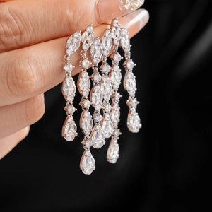 Macro shot of silver tassel earrings with zircon water drop crystals on a hand model