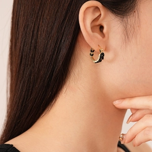 Macro shot of gold wheat-ear U-shaped hoop earrings with black marquise stones