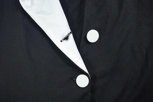 Detailed view of black dress with contrast white lapel and round button stitching