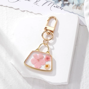 Handmade dry flower bag keychain with pink and yellow flowers in gold metal frame