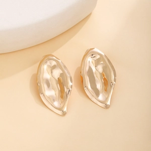 Detailed close-up of golden irregular teardrop earrings with textured hammered finish