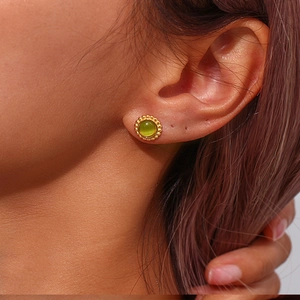 Close-up of olive green cat eye stud earring with gold-plated sunburst beaded edge