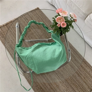 Dettaglio della borsa a mezzaluna in nylon verde chiaro con manico arricciato e zip