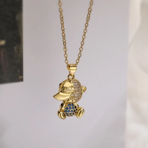 Macro shot of gold-plated teddy bear pendant with clear and blue crystals and COOL logo