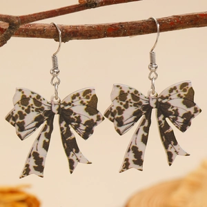 Detail van luipaardprint strik oorbellen hangend aan een natuurlijke houten tak decor