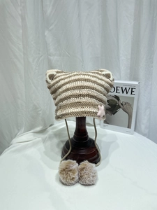 Detailed knit texture of cat ear beanie with pink stars, metal pins and fuzzy pom-poms