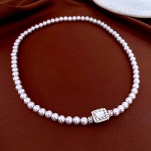 Macro view of vintage pearl necklace with zirconia square pendant on velvet background