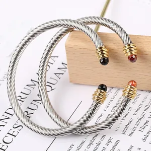 Macro detail of twisted cable stainless steel bangles with colorful gemstone ends