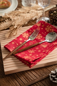 Gros plan sur des couverts en inox avec manche en bois sur une serviette de Noël rouge