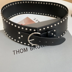 Detail of a vintage black leather wide belt with silver rivets on a textured box