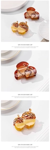 Close-up of amber and acorn style hair clips on a white plate with soft shadows