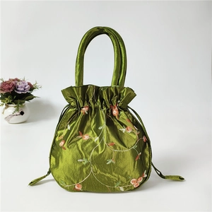 Detail of green silk drawstring bucket bag with exquisite floral embroidery and handle