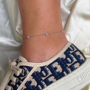 Elegant silver anklet with delicate blue flower charms and zircon stones on female ankle