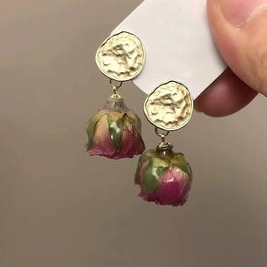 Golden round studs featuring real red rose buds encapsulated in clear resin pendants