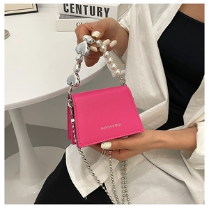 Detail of fuchsia mini bag featuring silver heart metal and pearl handle with chain strap