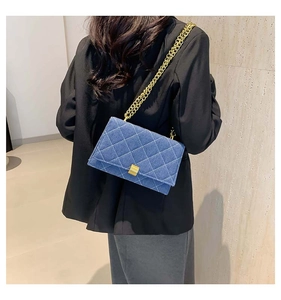 Detailed back view of a blue denim quilted crossbody bag with gold chain strap on a model