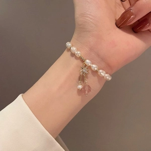 Detail of freshwater pearl bracelet with star pendant and pink gemstone on wrist