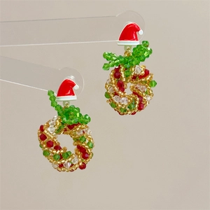 Close-up of handmade beaded Christmas tree earrings with red bow and Santa hat