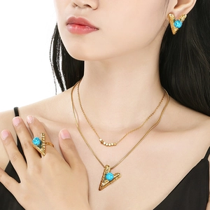 Gold stainless steel jewelry set with turquoise heart pendants worn by a professional model