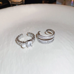 Close-up of silver-plated double layer rings featuring square zircon and pearl accents