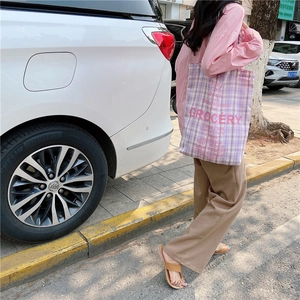 Outdoor shot of a purple checkered canvas tote bag with pink grocery text graphics