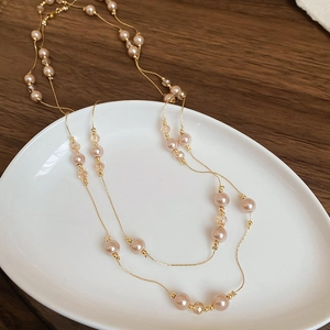 Détail d'un long collier de perles et cristaux disposé sur un plateau en céramique