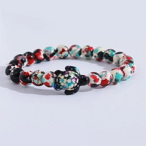 Detailed view of colorful speckled beads and a small sea turtle charm on the stretch bracelet