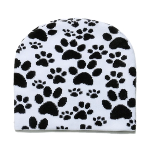 Close-up detail of knitted beanie with black animal paw prints on white fabric