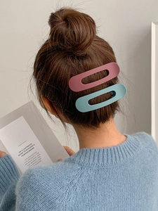 Close-up of matte pink and blue hair clips on a model's hair for a stylish look