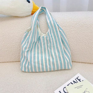 Detail of blue and white striped canvas tote bag on cozy sofa with fashion magazine