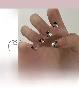 Detail of French press-on nails with gold tips and black stars on nude base