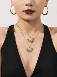 Gros plan d'un ensemble de colliers pendentif soleil et boucles d'oreilles dorés