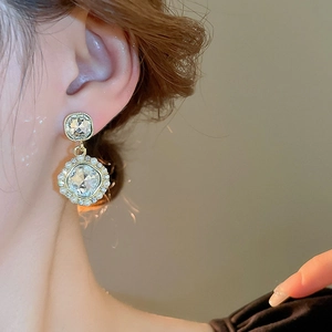 Close-up of vintage gold earrings with square zircon and small pearls on model