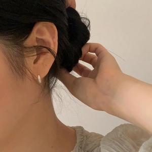 Close-up of minimalist sterling silver micro-pave hoop earrings worn on a female ear lobe