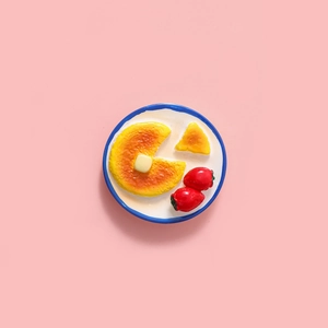 Miniature resin breakfast pancake magnet with butter and strawberries on a white plate