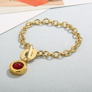 Detail of gold link bracelet with red gemstone pendant and minimalist OT toggle clasp