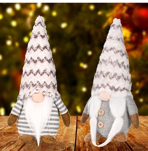 Detail of two Christmas gnomes with grey knitted hats on a wooden surface with bokeh lights