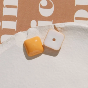 Macro shot of orange and white square resin beads for DIY jewelry making with smooth finish