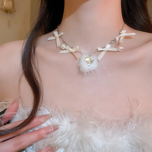 Close-up of white ribbon bow necklace with pearl and heart rhinestone plush ball pendant