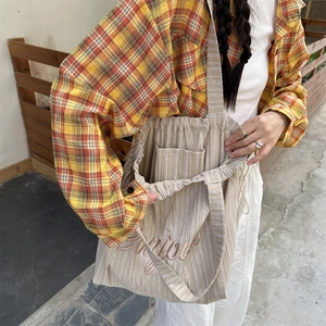 Detail of embroidered Bonjour text and drawstring closure on striped canvas tote bag