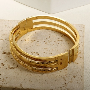18K gold-plated sleek metal and textured snake chain bangle on a beige stone surface