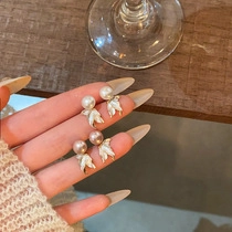 Detail showing two pairs of pearl drop earrings with white petal accents held in hand