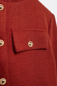 Gros plan sur le tweed caramel avec bouton doré et détail de poche à rabat