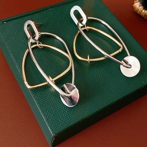 Gros plan de boucles d'oreilles géométriques bicolores sur un coffret cadeau vert