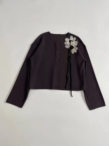 Detailed view of dark grey ribbed knit cardigan with white floral applique and black ribbons