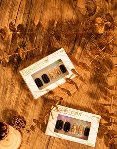 Detail view of black and gold press-on nails with glitter and rhinestones in gift boxes